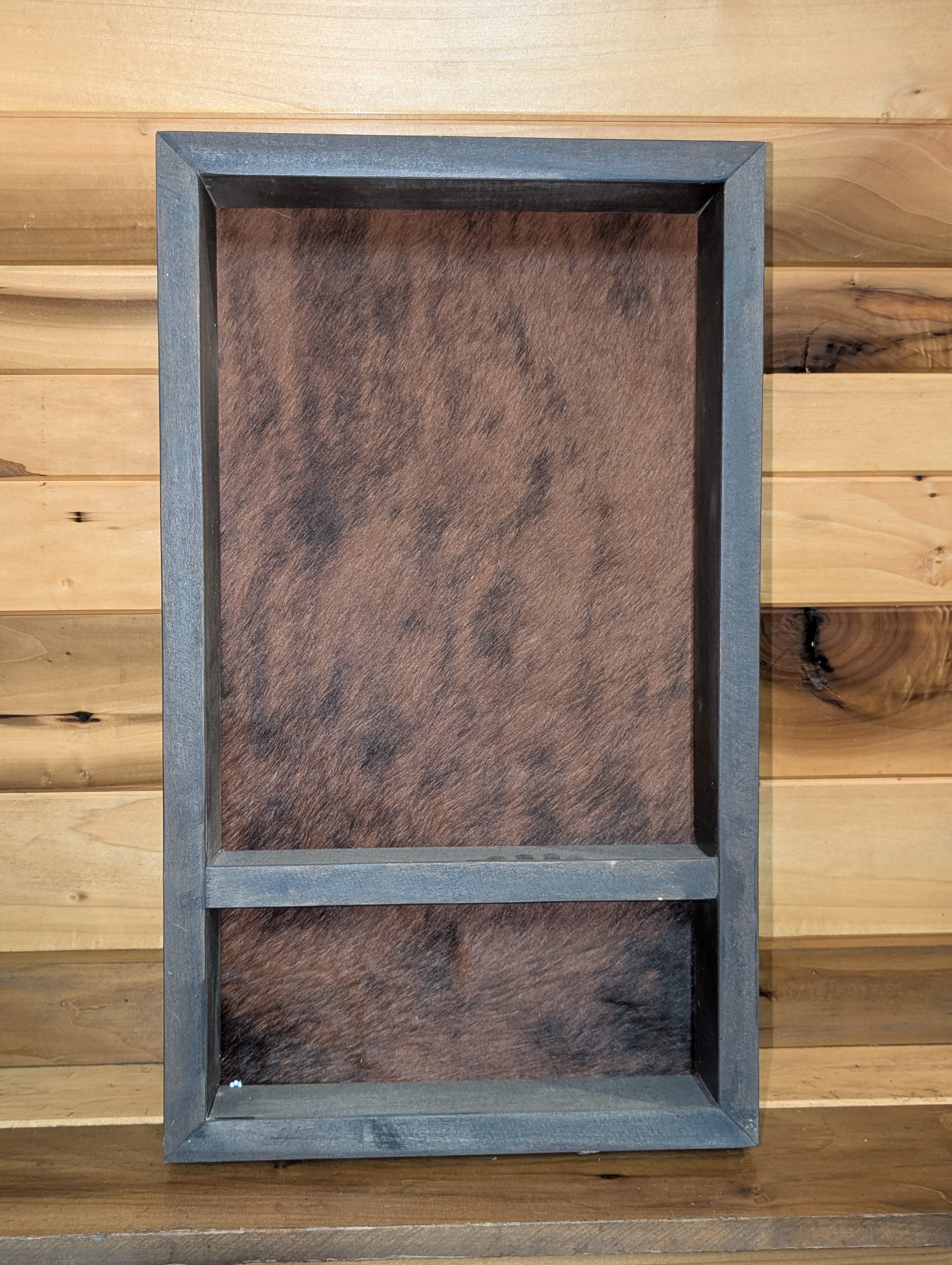 A burnt hickory wood belt buckle display with a genuine brindle cowhide rug in the back. 
