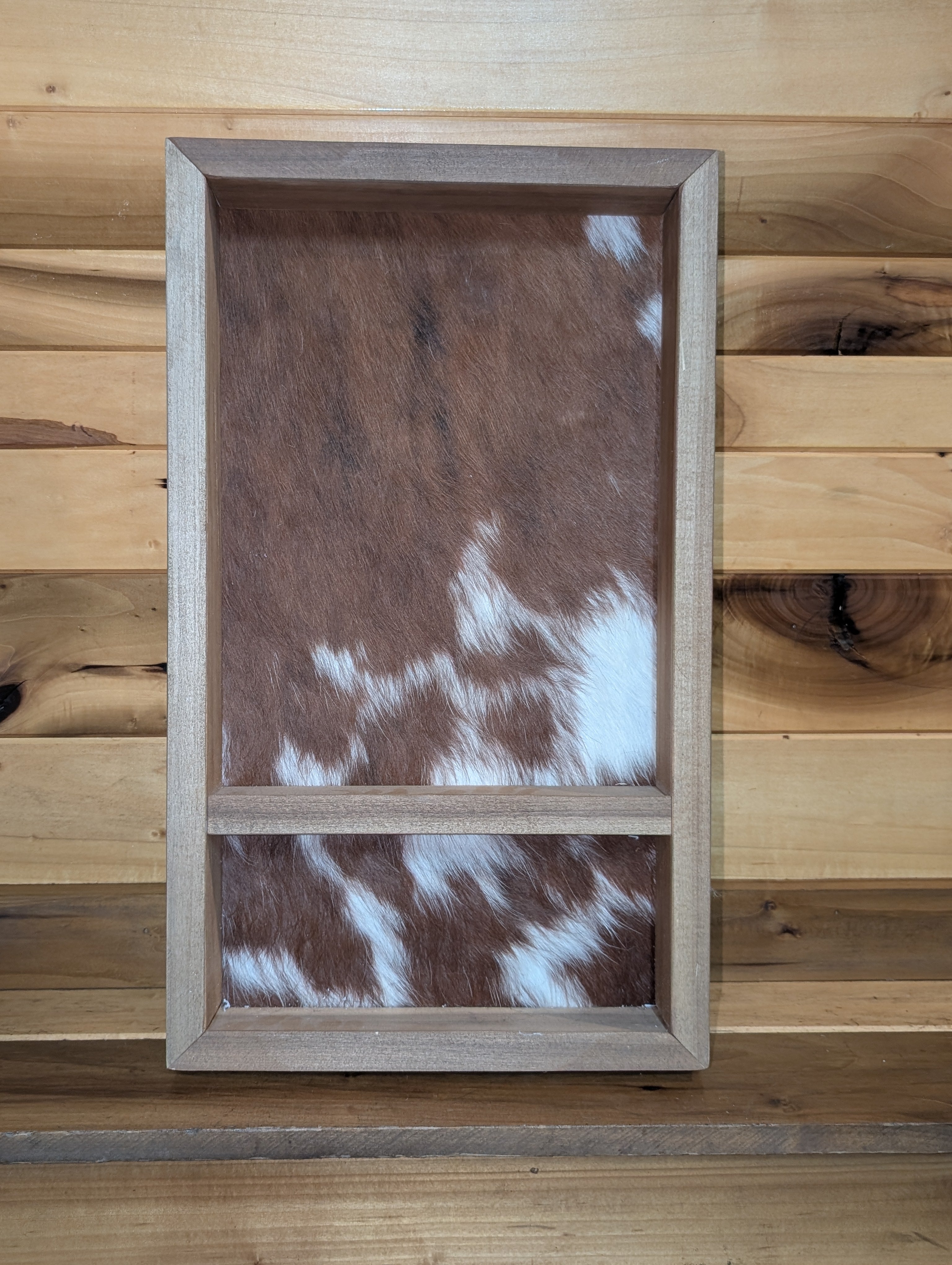 A custom wooden belt buckle case with a genuine red and white cowhide backing