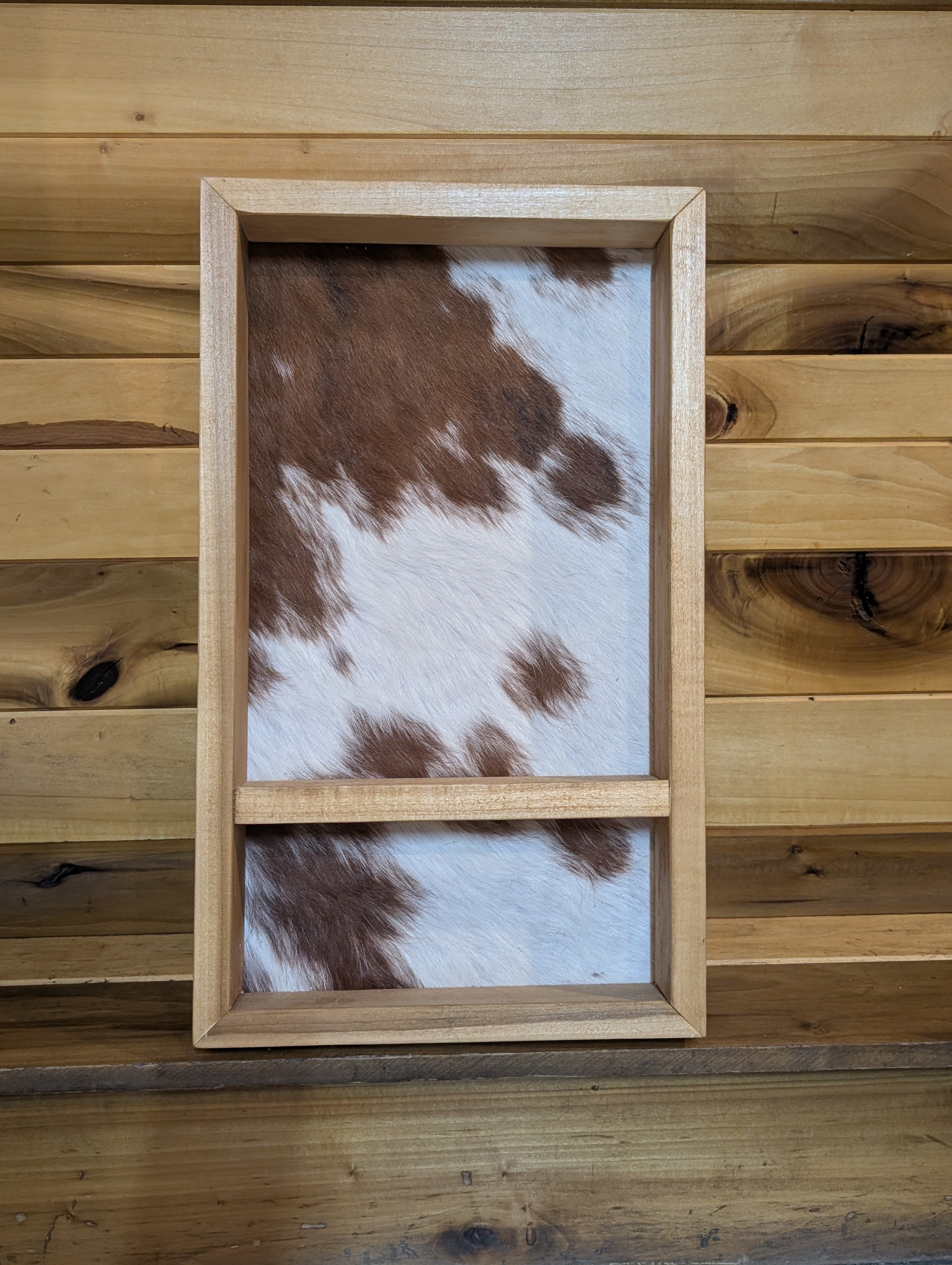 A custom belt buckle display with a genuine white and red cowhide back.