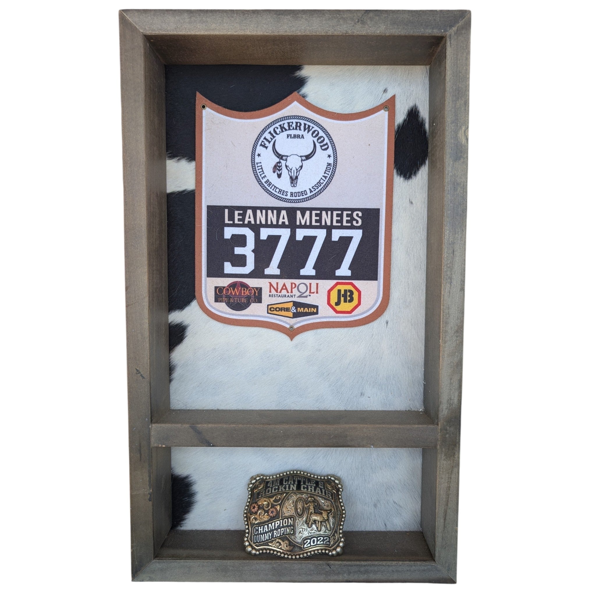 A rustic wooden belt buckle display case with a unique black and white cowhide background. The upper section holds a competition back number & up to 4 belt buckles.