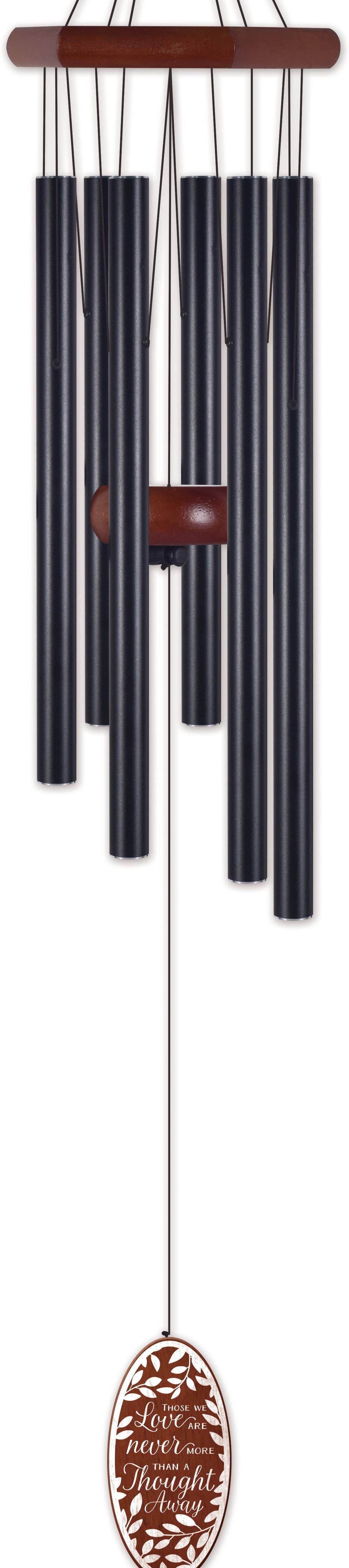 A wind chime with six dark tubes hanging from a brown wooden frame, with a matching oval brown hanging ornament below featuring the engraved text 'Love Never Wears Disguise'.