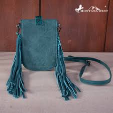 Teal leather handbag with fringes on a wooden surface