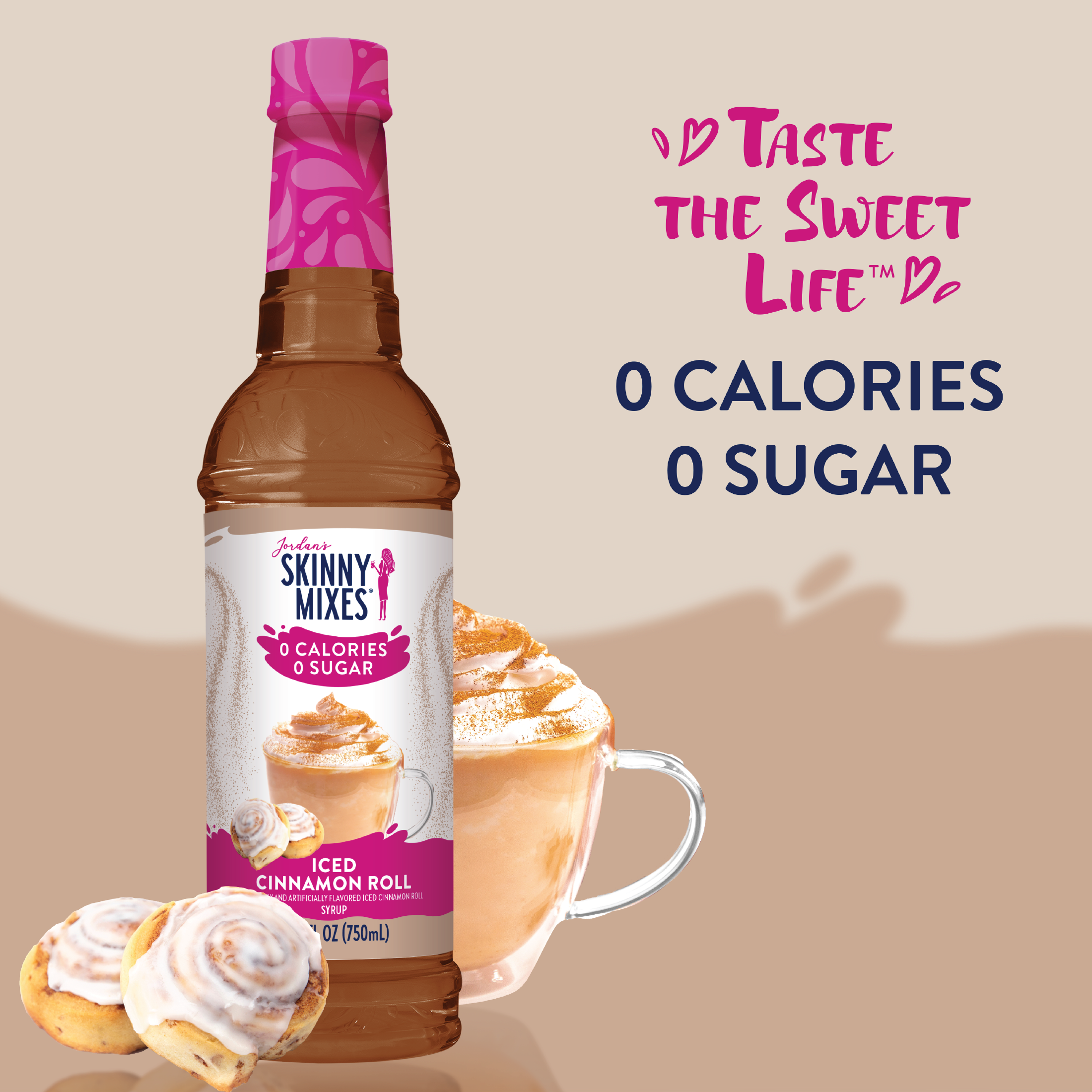 Bottle of Skinny Mixes syrup with a cup of iced cinnamon roll coffee and a cinnamon roll on a beige background.