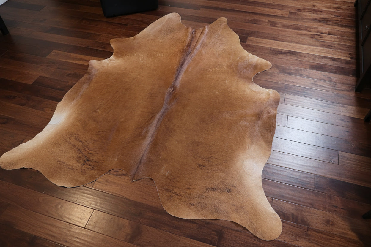 Brown/reddish cowhide rug on a wood floor