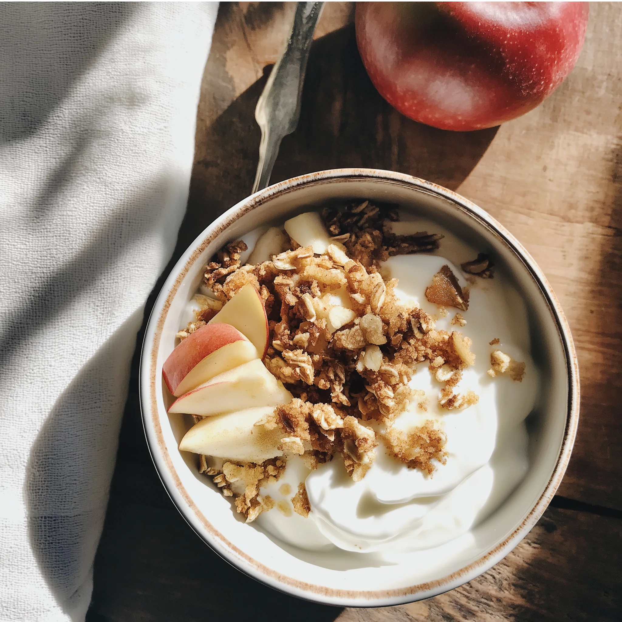 Yogurt bowl flavored with Jordan's Skinny Mix Apple Crisp syrup with granola and apple slices on a wooden table