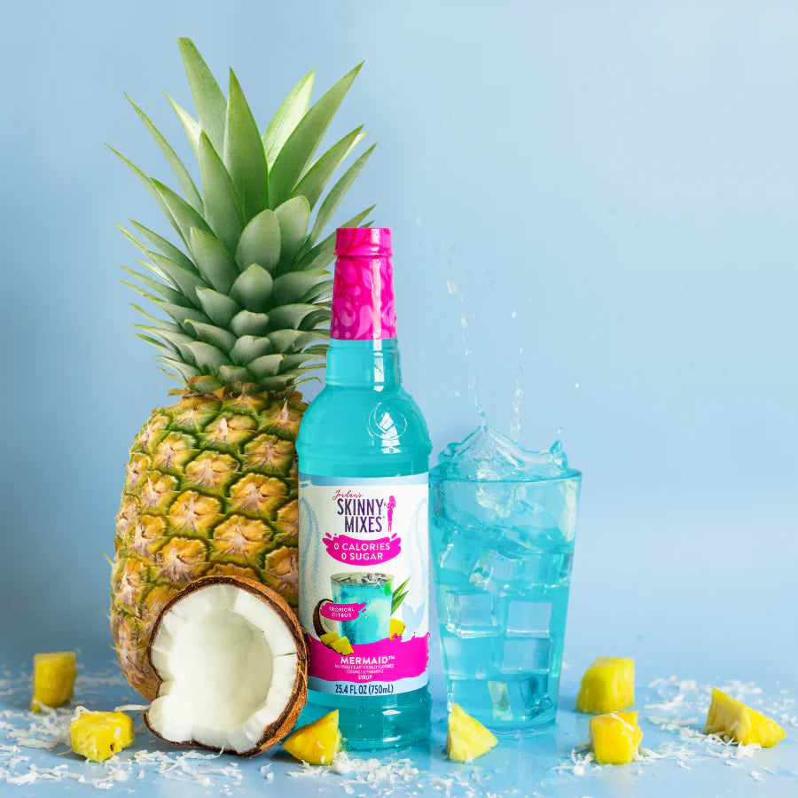 Jordan's Skinny Mixes Mermaid flavored bottle with glass of refreshing drink flavored drink  with a pineapple, coconut.