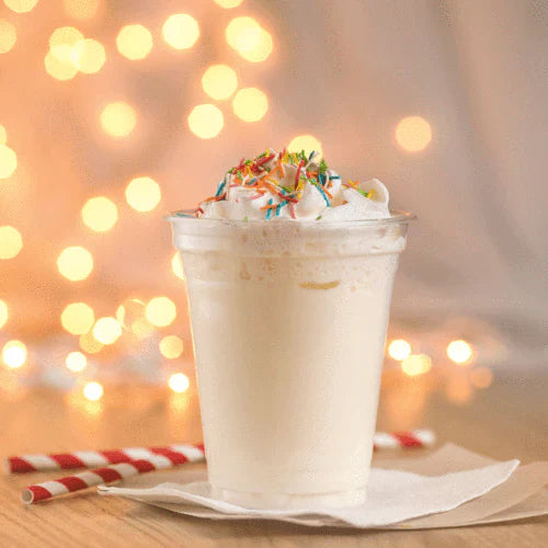 Jordan's Skinny Mix Sugar Cookie Syrup flavored Ice cream shake with whipped cream and sprinkles on a wooden surface with blurred lights in the background