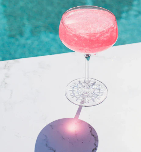 Jordan's Skinny Mix Fairy Dust adult beverage in a long stem martini glass next to pool.