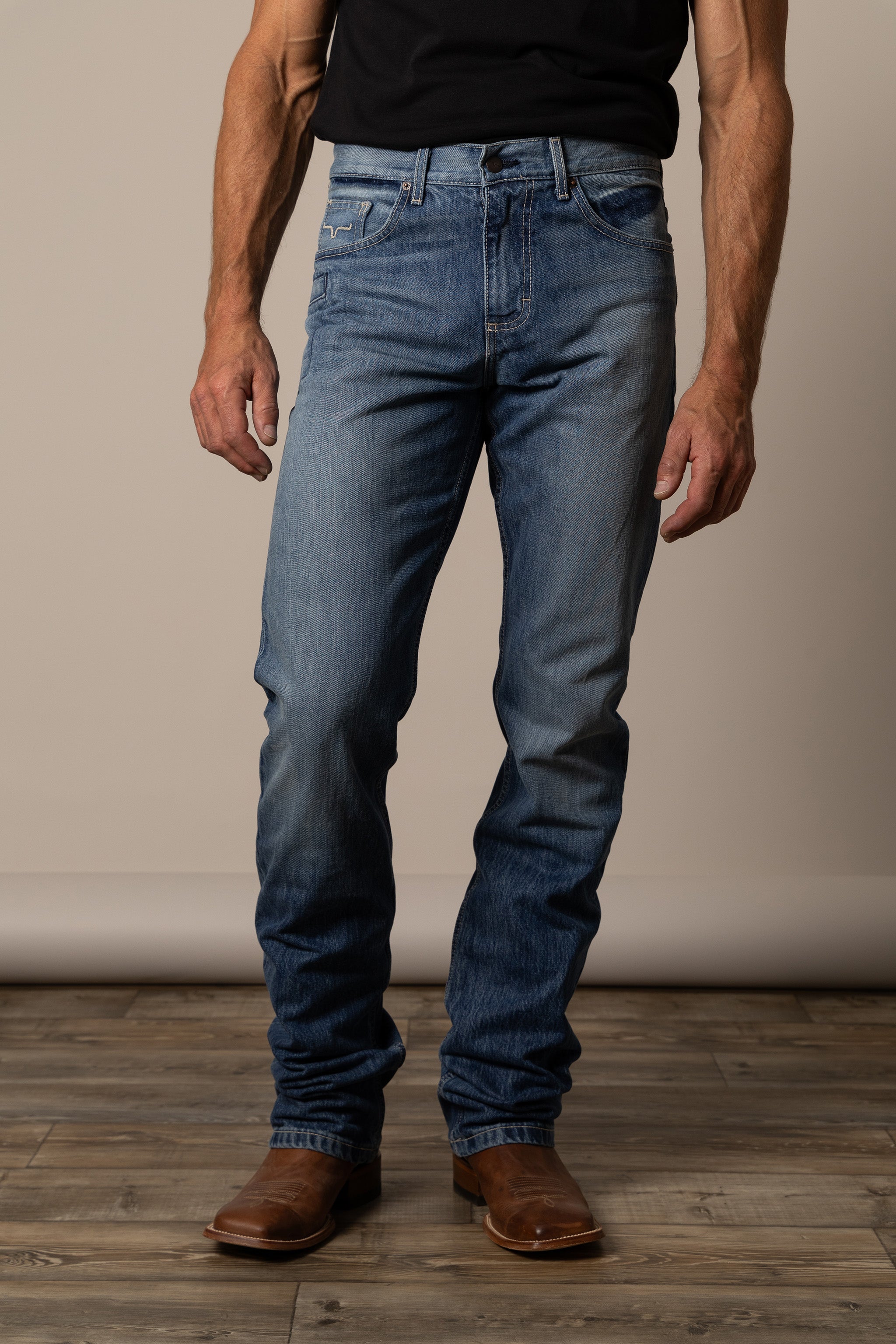 Person wearing Kimes Ranch blue jeans  in the style James and brown boots.
