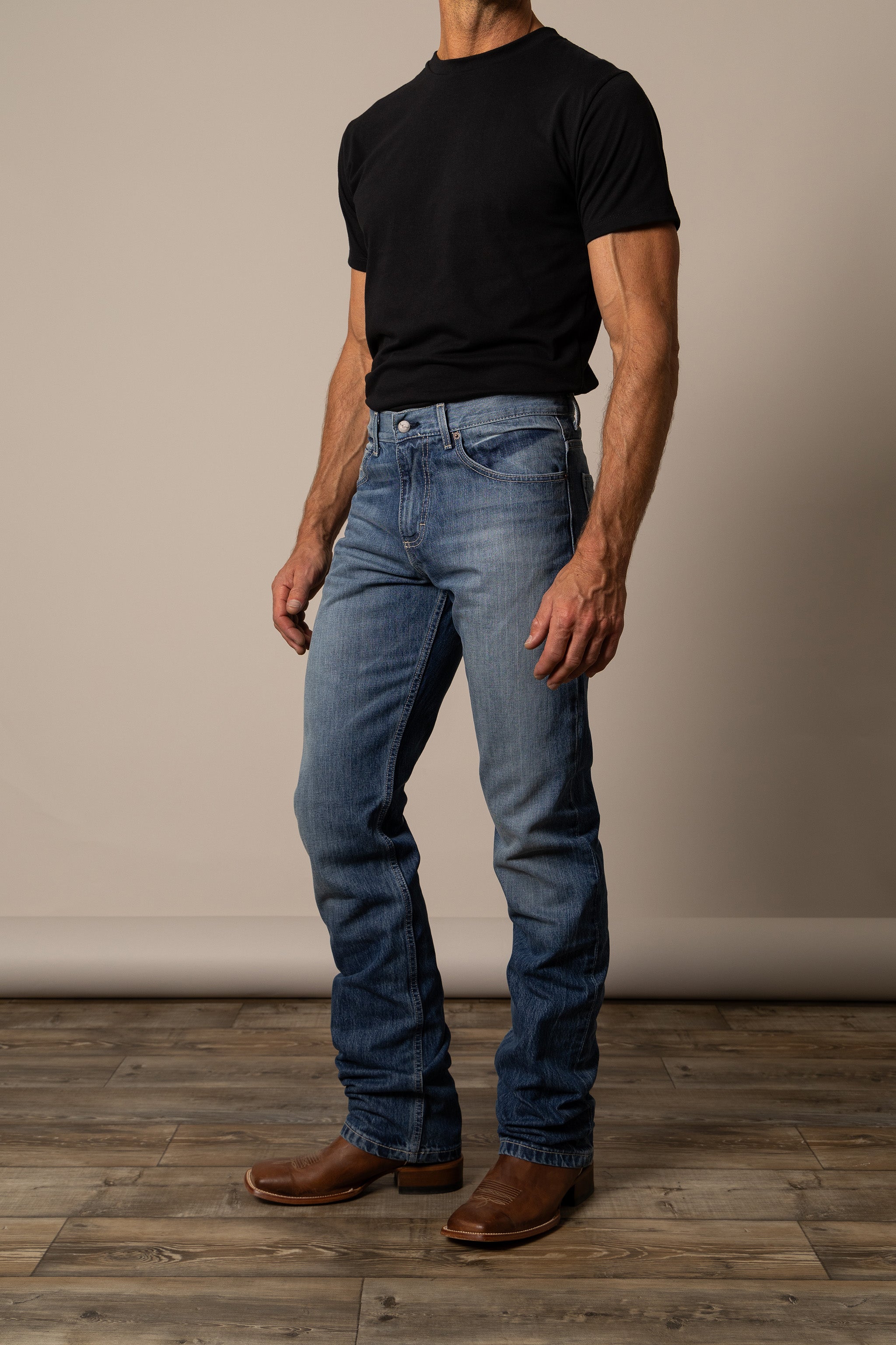 Person wearing Kimes Ranch blue jeans  in the style James, paired with boots and a black shirt