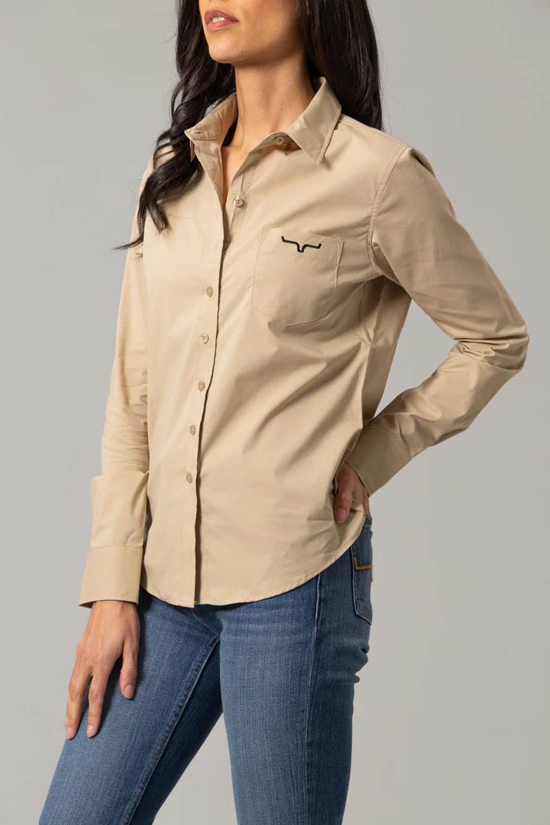 Woman wearing a beige long-sleeve shirt with a kimes ranch logo.