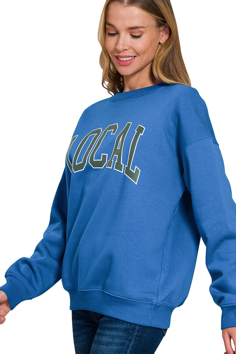 Left side view of a lady wearing a blue sweatshirt with LOCAL on it.