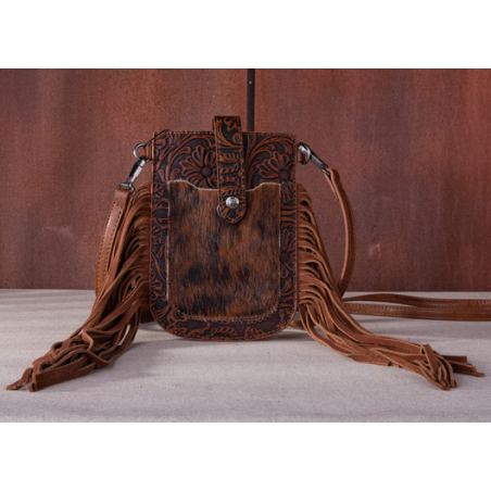 Brown leather crossbody bag with fringes on a gray surface and brown background