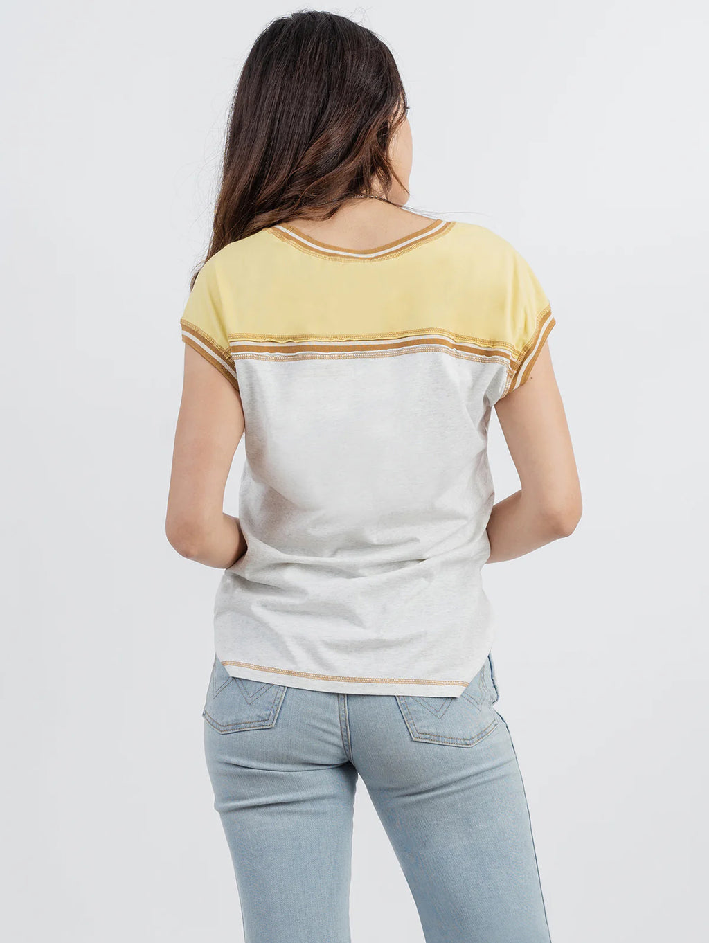 Woman wearing a yellow and white striped shirt with blue jeans on a white background
