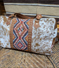 Cowhide patterned bag with geometric design on a textured surface
