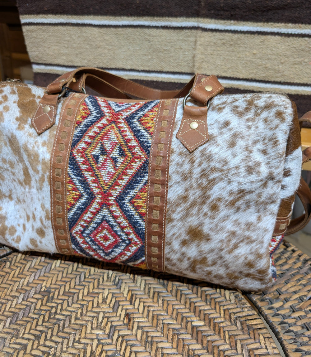 Cowhide patterned bag with geometric design on a textured surface