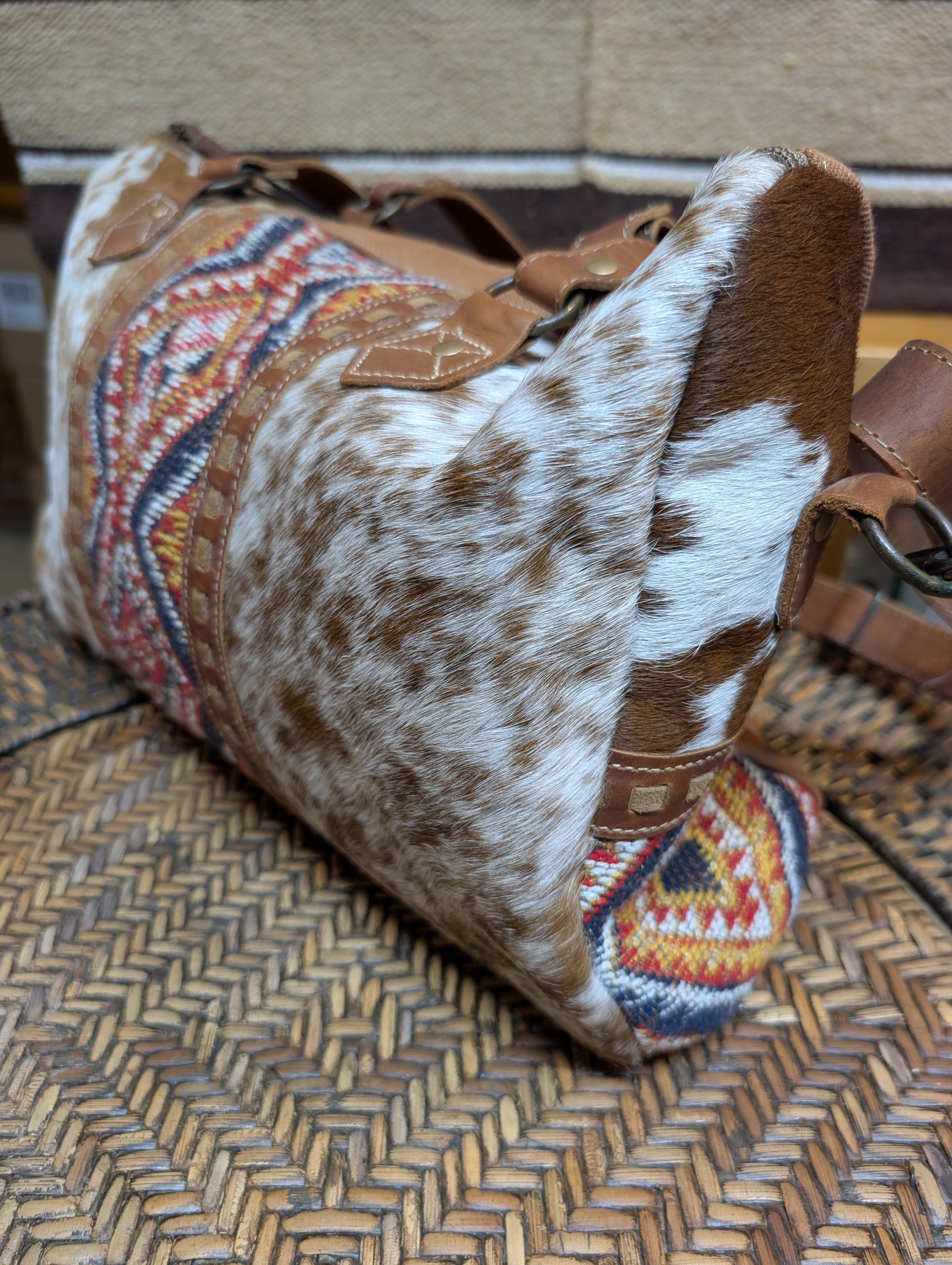Brown and white patterned bag with decorative strap on a woven surface