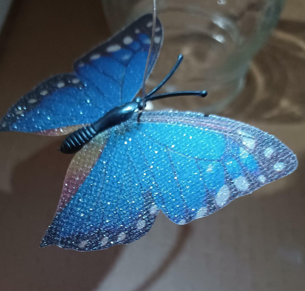 Blue glittery butterfly toy held by a hand with a blurred background