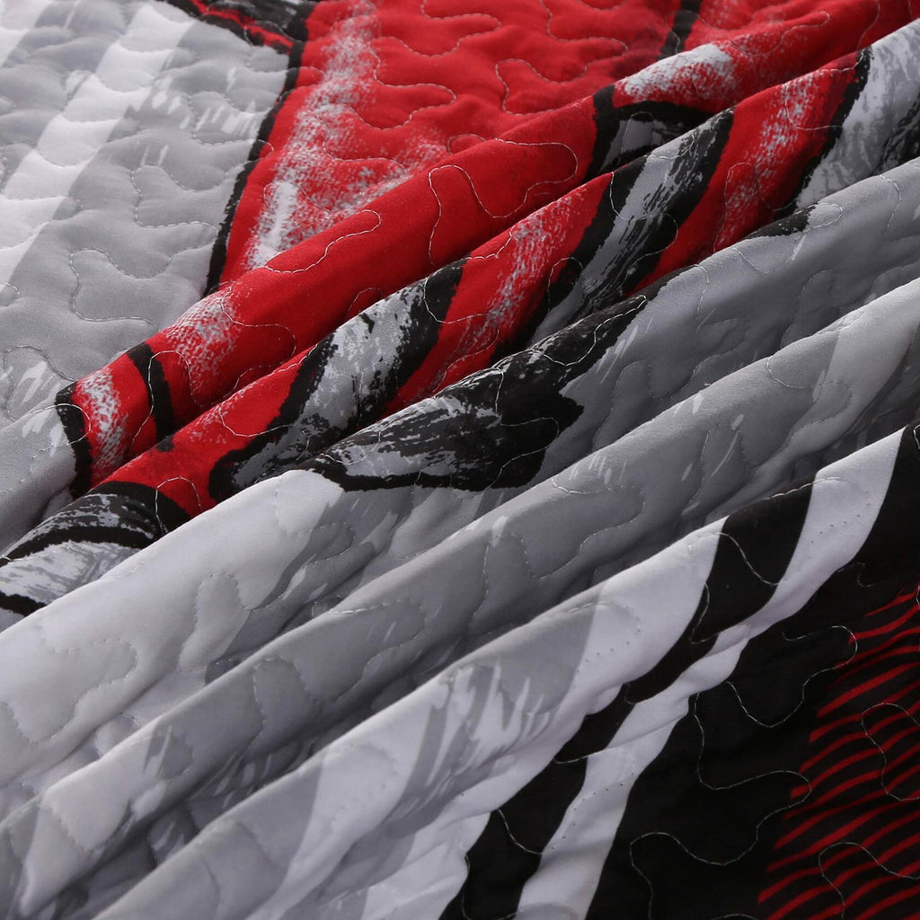 Close-up of a quilt with red, black, and gray patterns
