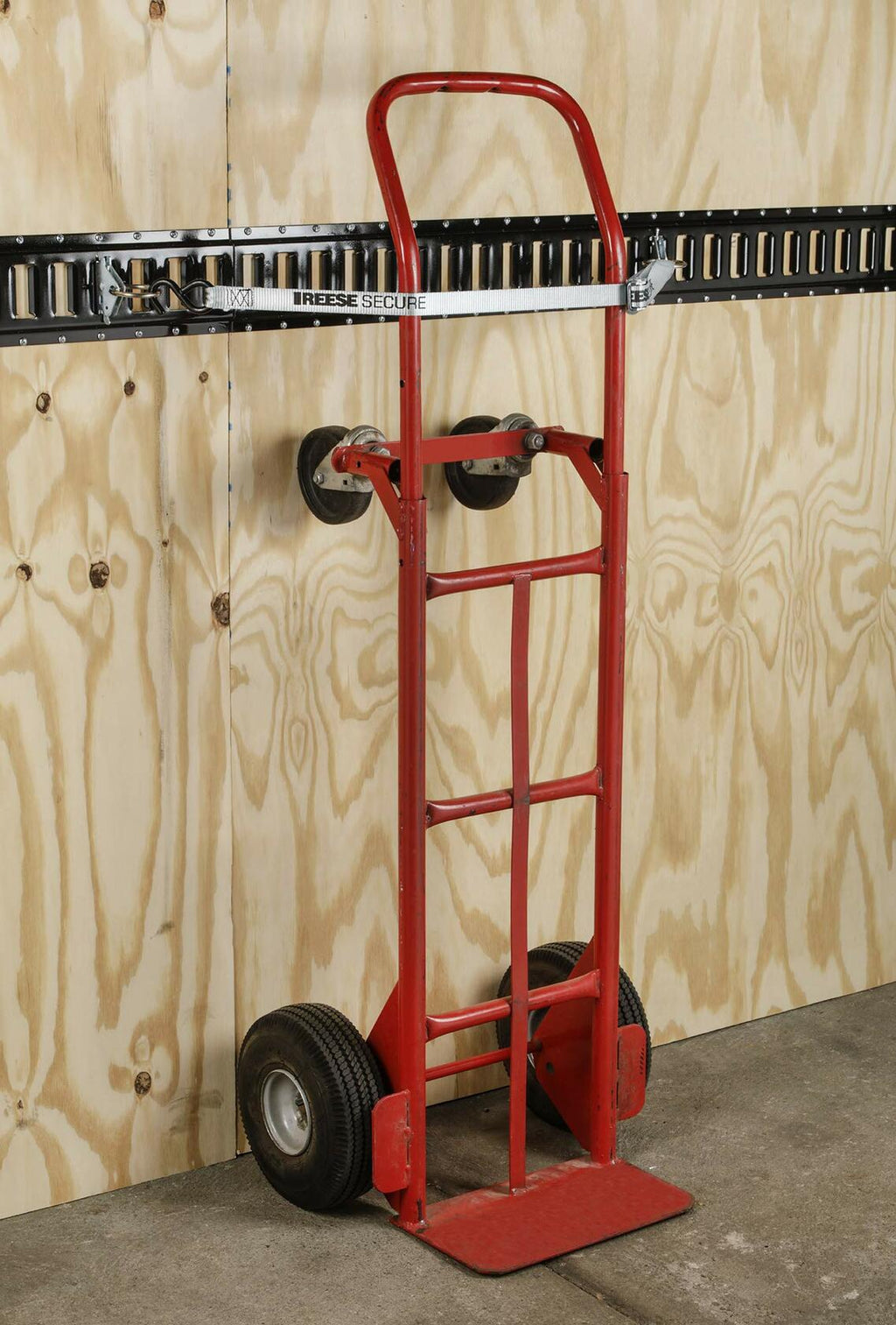 Red hand truck against a wooden panel wall