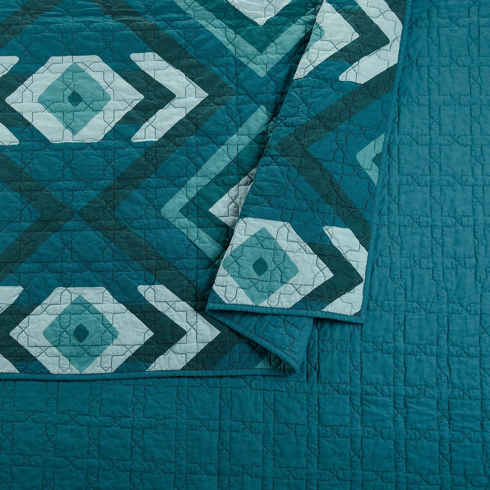 Teal quilt with geometric pattern on a matching fabric background