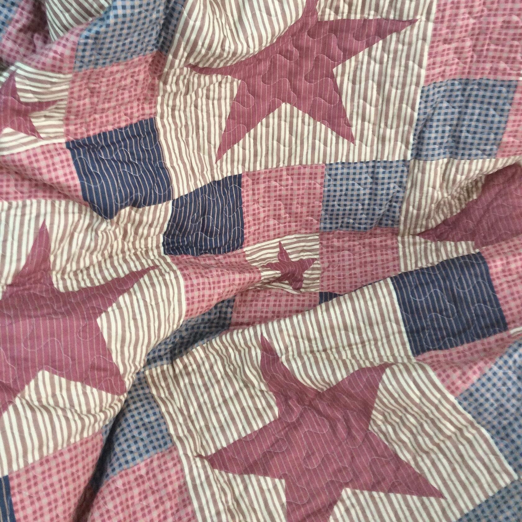Quilt with star patterns in red, white, and blue.