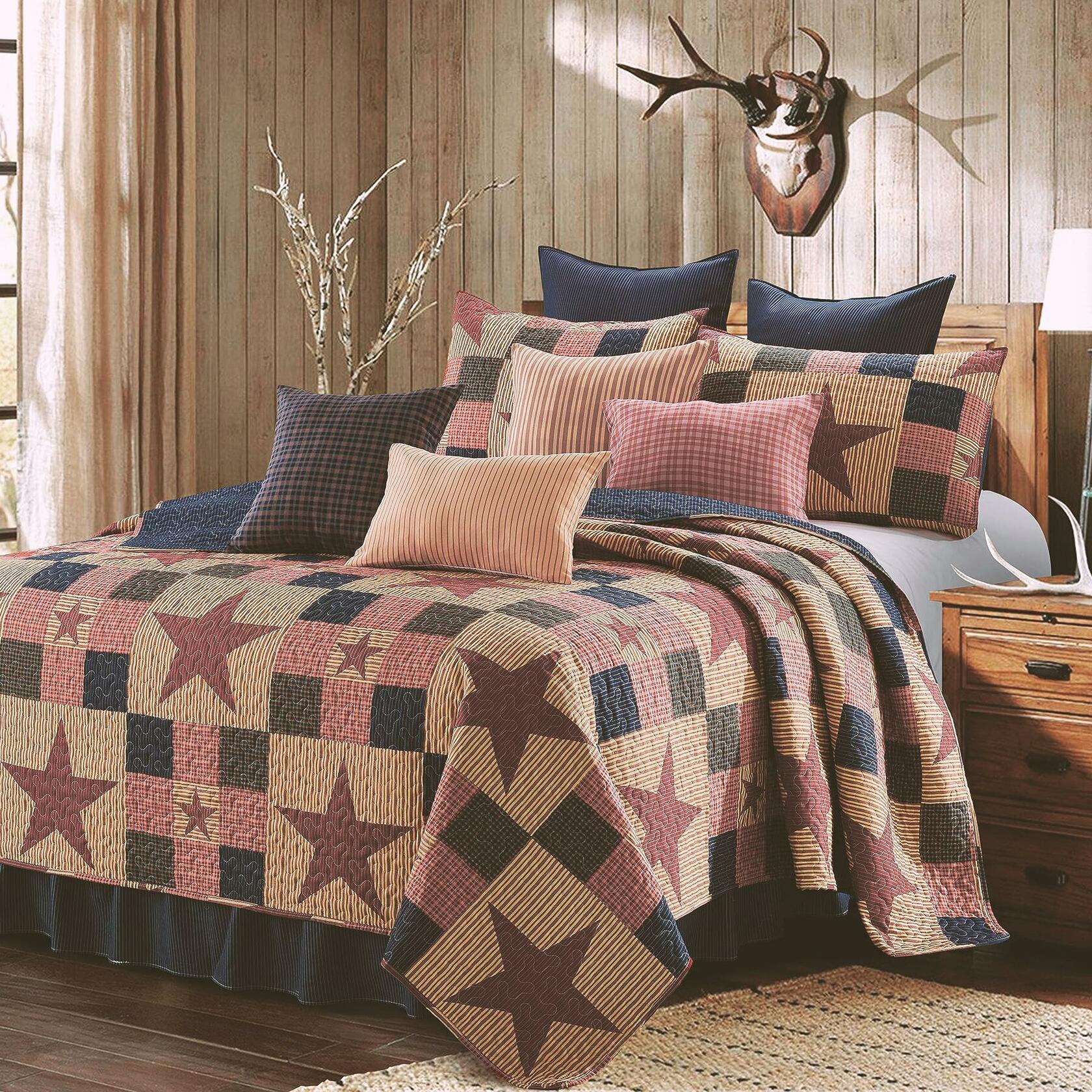 Bedroom with a star-patterned quilt and pillows on a bed, wooden headboard, and deer head mount on wall.