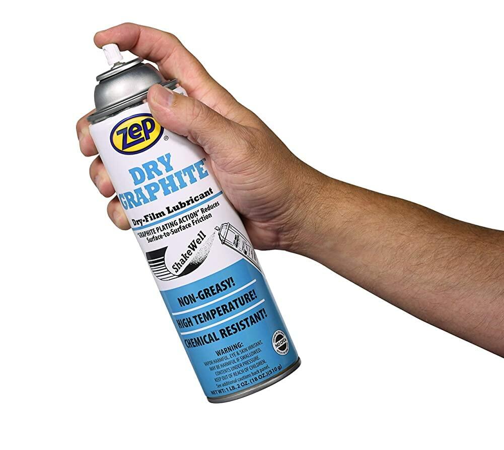 Hand holding a can of Zep Dry Graphite lubricant against a white background