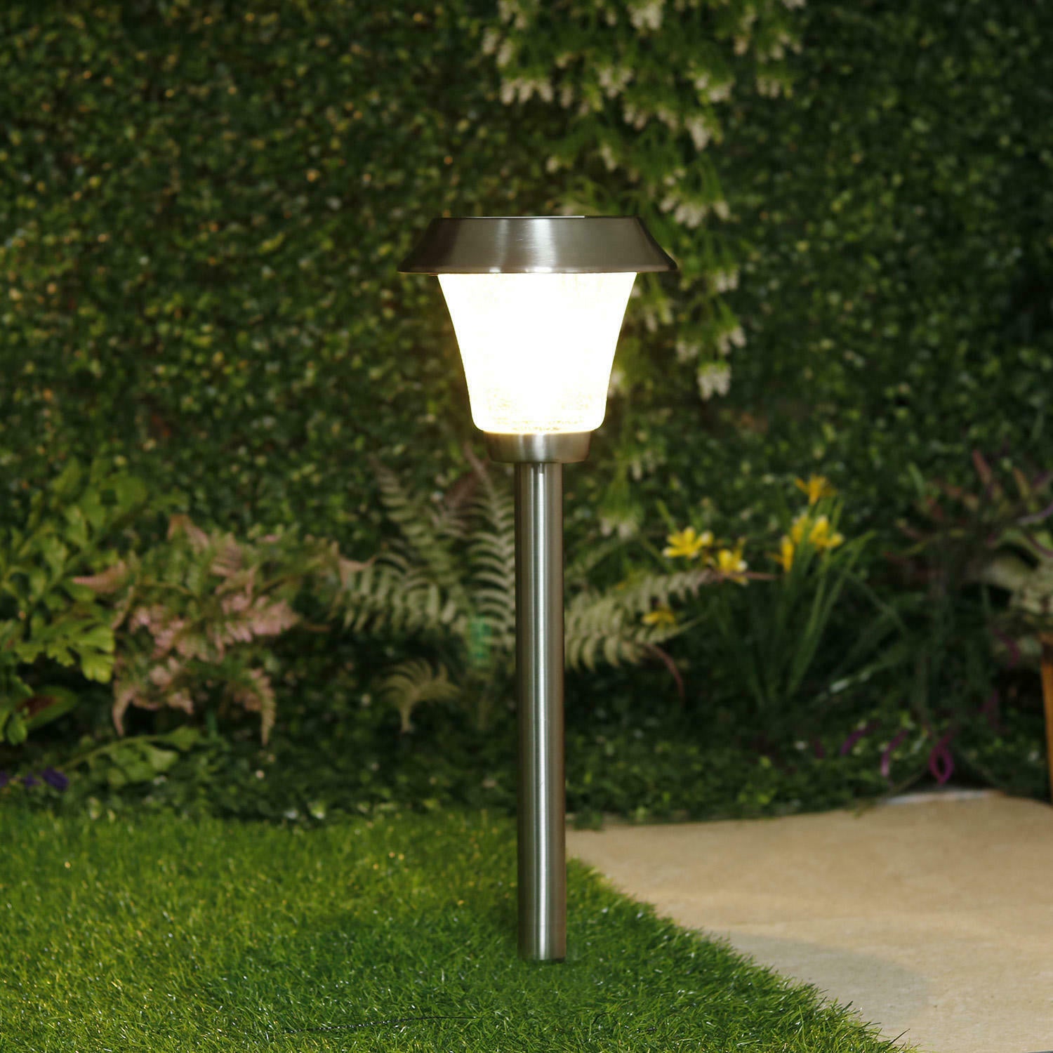 Garden light post with a glowing white light in a garden setting