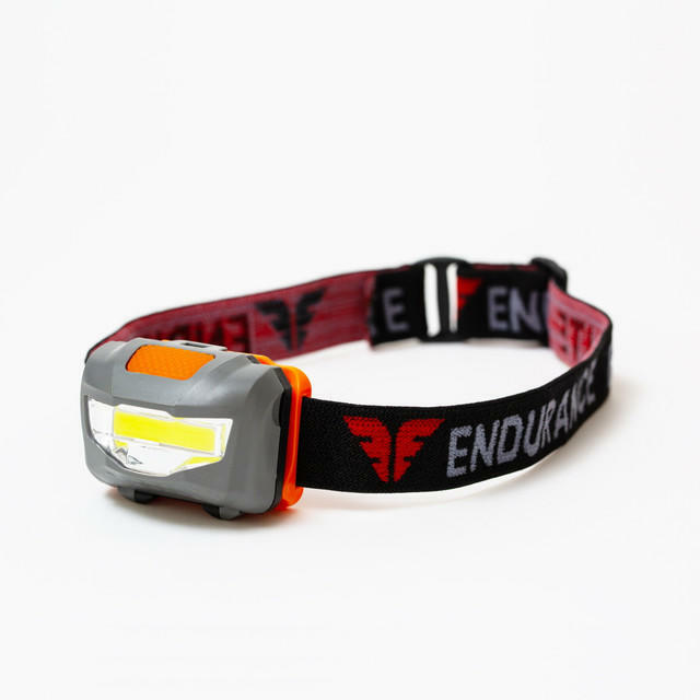 Headlamp with red and black strap on a white background