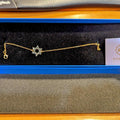 Gold bracelet with a star design on a black display stand.