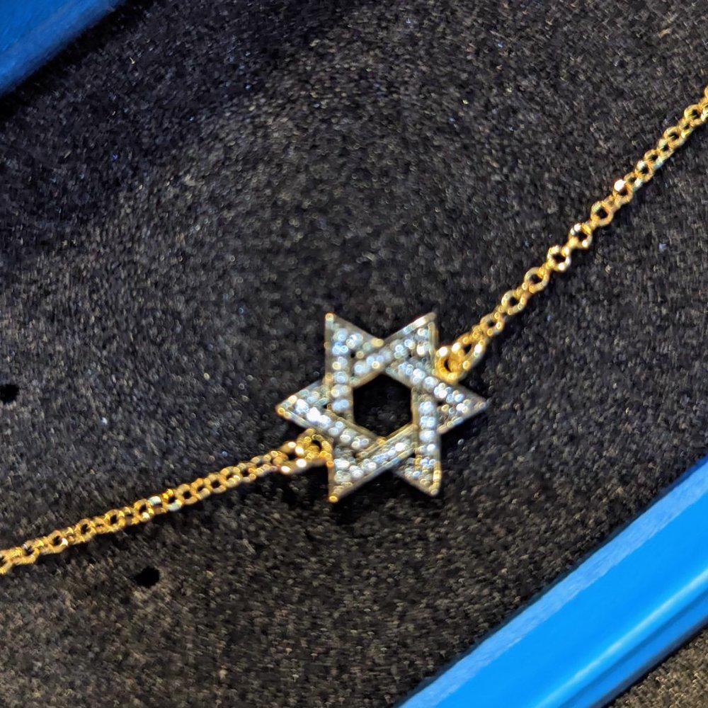 Gold bracelet with a Star of David charm on a textured surface