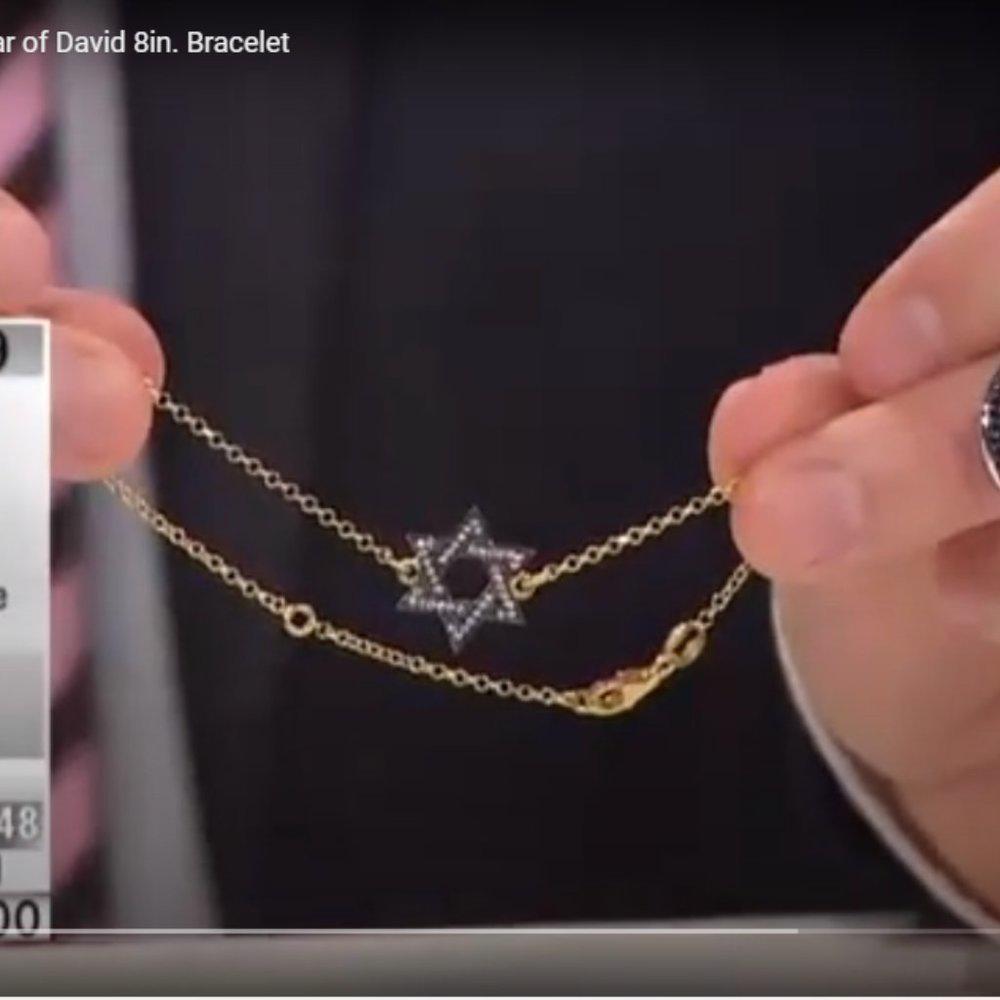 Gold bracelet with a Star of David charm held by hands against a dark background