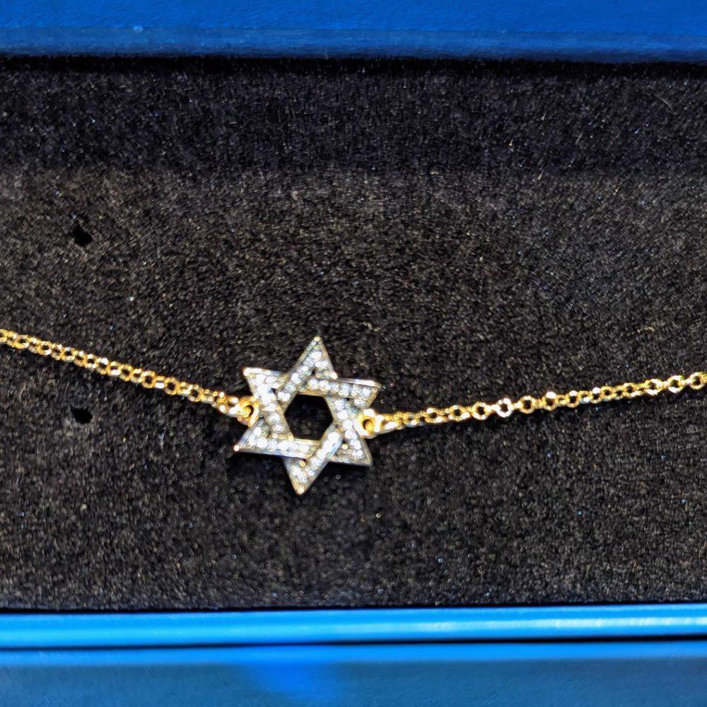 Gold bracelet with Star of David charm on a black background