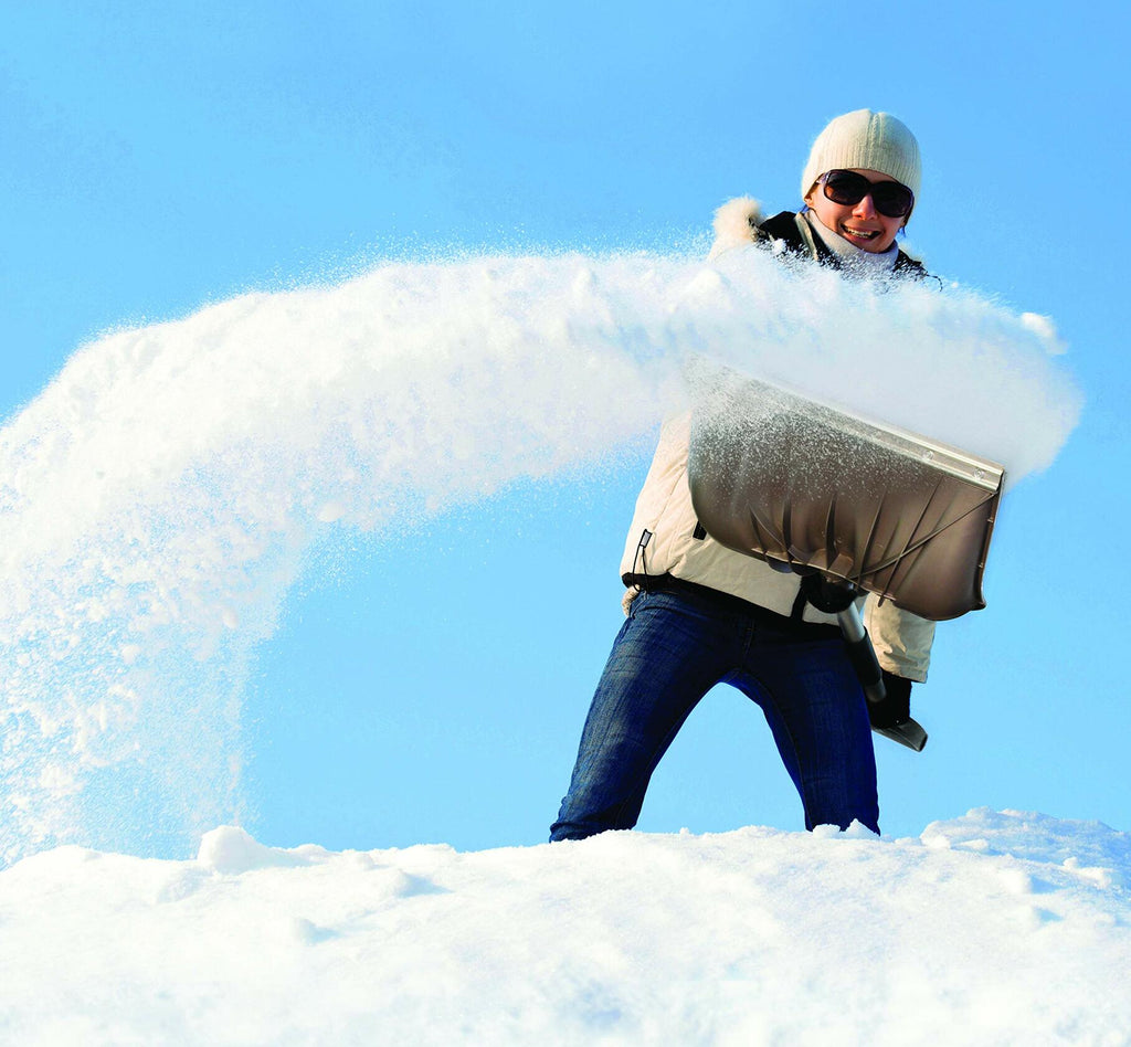 Person in winter clothing holding a large block of ice against a blue sky