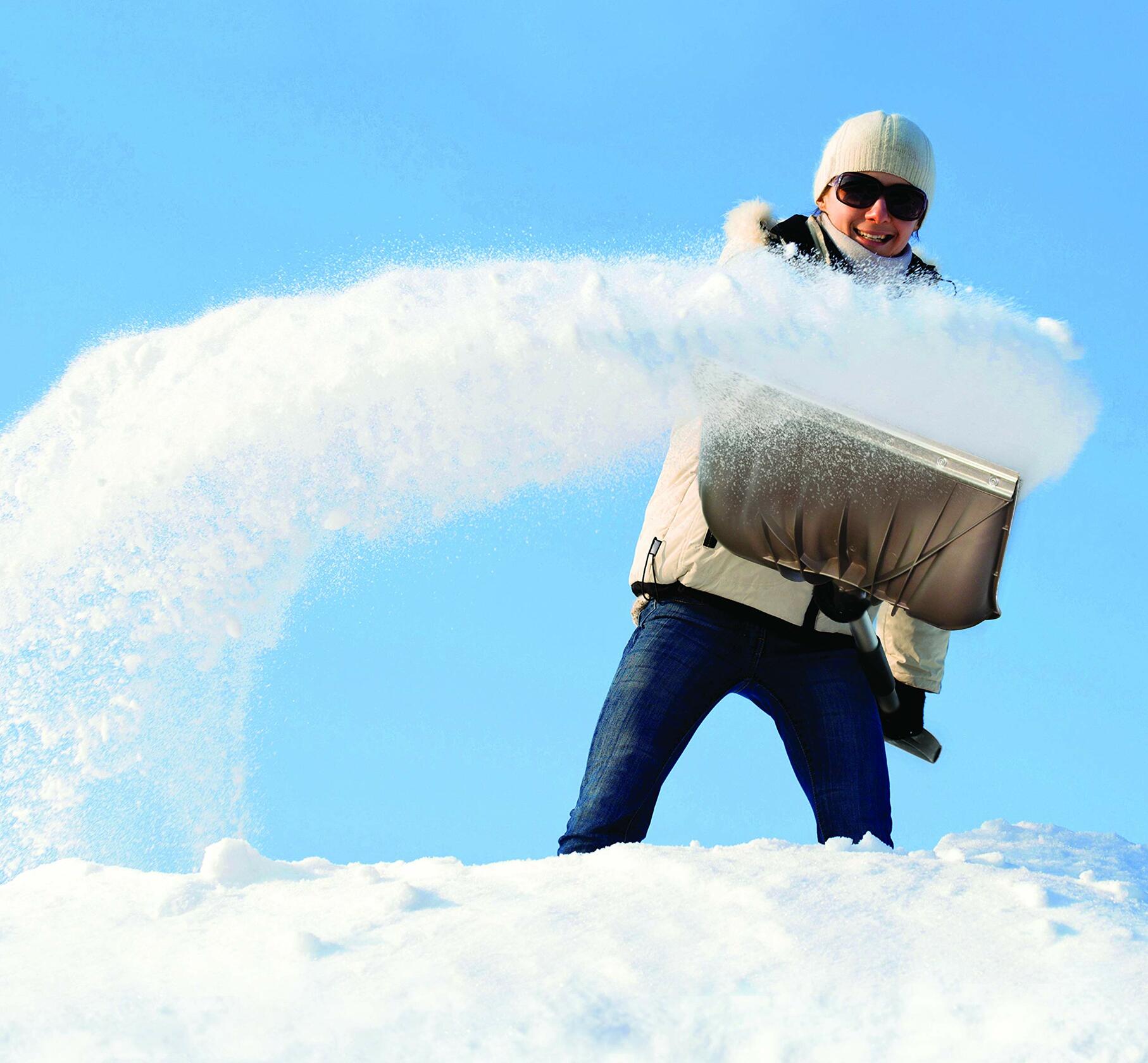 Person in winter clothing holding a large block of ice against a blue sky