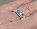Silver ring with intricate design on a person's finger