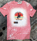 Pink t-shirt with graphic design on a textured surface