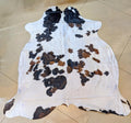 Cowhide rug with black, brown, and white pattern on a tiled floor.