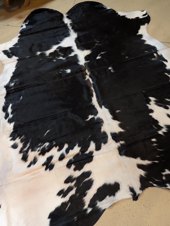 Black and white cowhide rug on a tan floor