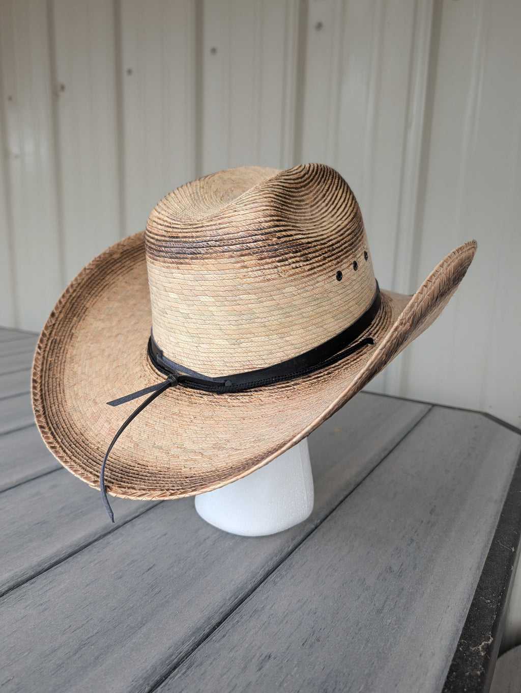 Back view of woven palm leaf Western cowboy hat with a black hat band