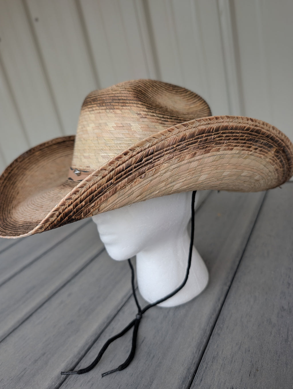 Side profile of woven palm leaf Western cowboy hat featuring black stampede string