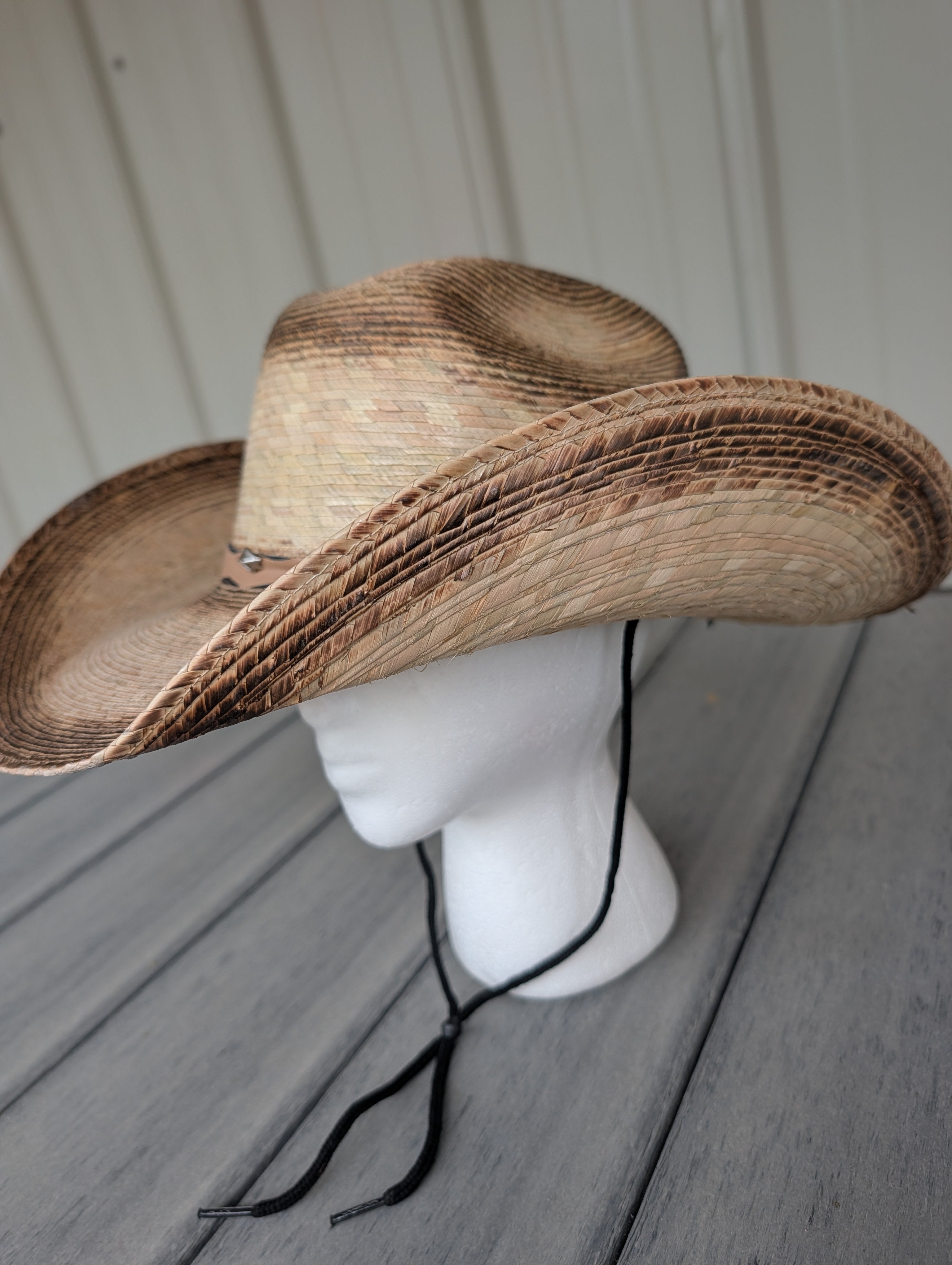 Side profile of woven palm leaf Western cowboy hat featuring black stampede string